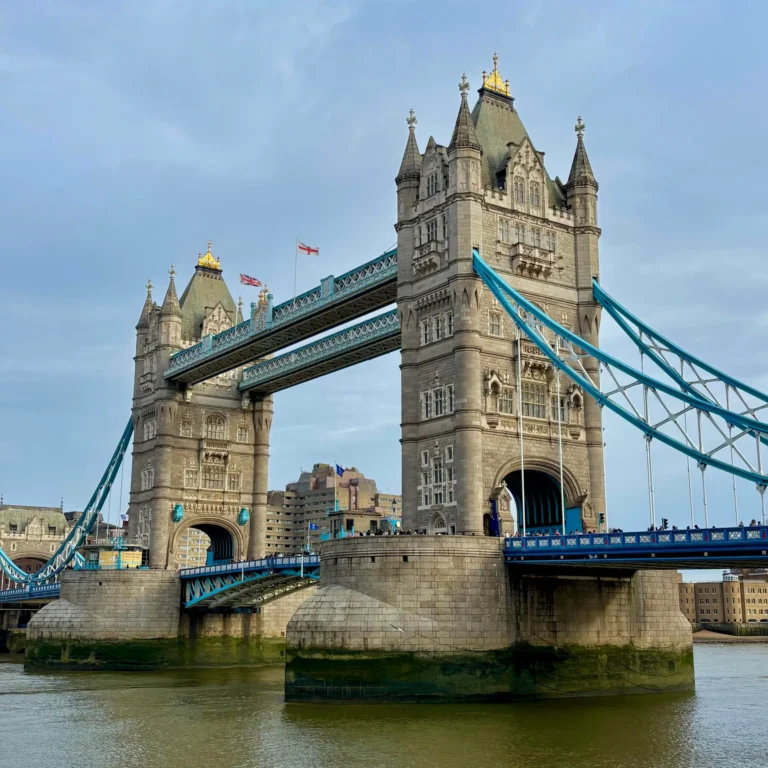 View of the Tower of London, a historic fortress and iconic landmark, showcasing its medieval architecture against the cloudy sky.