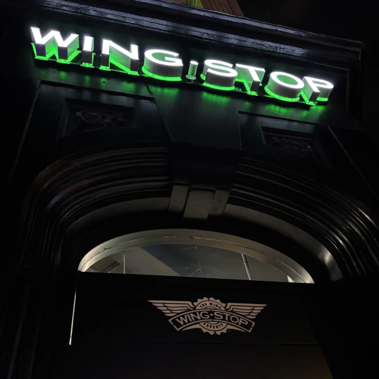 Neon light sign of Wingstop, a popular fast food chain known for its delicious wings, glowing at night.
